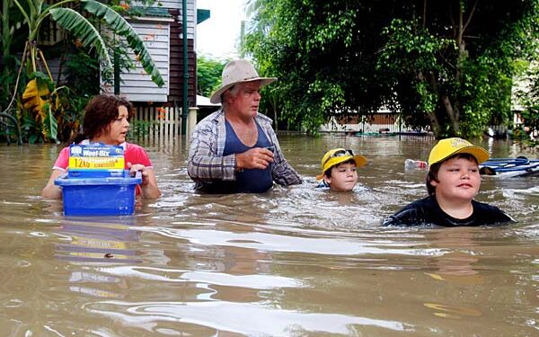 Paul Barnes and Mandy Greene with their sons, Patrick, right, and Bradley, wade through chest high flood water to return to their house to find their insurance documents in Rockhampton.