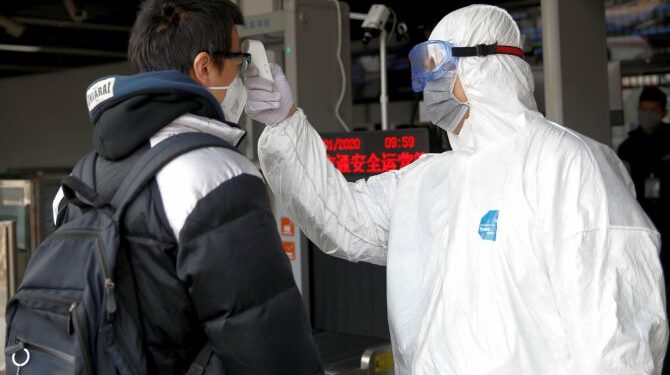 A worker in protective suit uses a thermometer to check the temperature of a man while he enters the Xizhimen subway station, as the country is hit by an outbreak of the new coronavirus, in Beijing, China January 27, 2020. REUTERS/Carlos Garcia Rawlins - RC24OE94QMQK