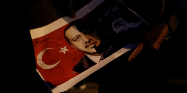 A Kurd living in Greece holds a poster depicting Turkish President Recep Tayyip Erdogan during a demonstration against the Turkish offensive on Kurdish forces in northwest Syria, in Athens, Greece, January 23, 2018. REUTERS/Alkis Konstantinidis - RC16FB9E79B0