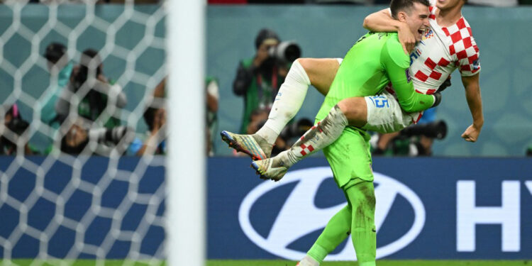 Croatia's goalkeeper #01 Dominik Livakovic celebrates with Croatia's midfielder #15 Mario Pasalic after winning the Qatar 2022 World Cup round of 16 football match between Japan and Croatia at the Al-Janoub Stadium in Al-Wakrah, south of Doha on December 5, 2022. (Photo by Ina Fassbender / AFP)