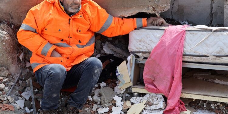 Mesut Hancer holds the hand of his 15-year-old daughter Irmak, who died in the earthquake in Kahramanmaras, close to the quake's epicentre, the day after a 7.8-magnitude earthquake struck the country's southeast, on February 7, 2023. - Rescuers in Turkey and Syria braved frigid weather, aftershocks and collapsing buildings, as they dug for survivors buried by an earthquake that killed more than 5,000 people. Some of the heaviest devastation occurred near the quake's epicentre between Kahramanmaras and Gaziantep, a city of two million where entire blocks now lie in ruins under gathering snow. (Photo by Adem ALTAN / AFP)